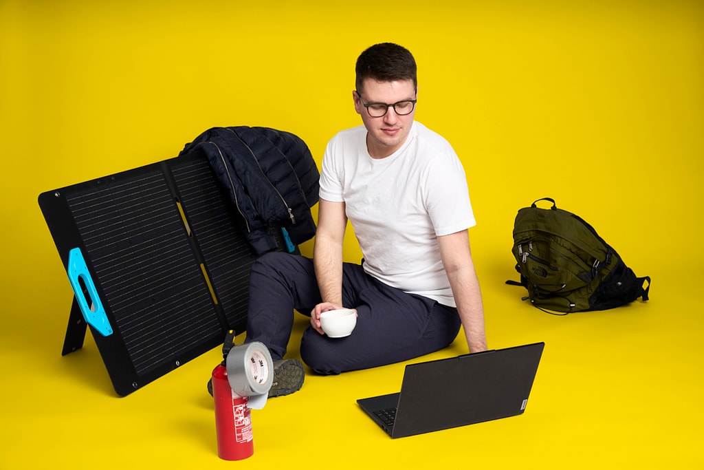 Mig med solpanel, laptop og udstyr foran gul baggrund